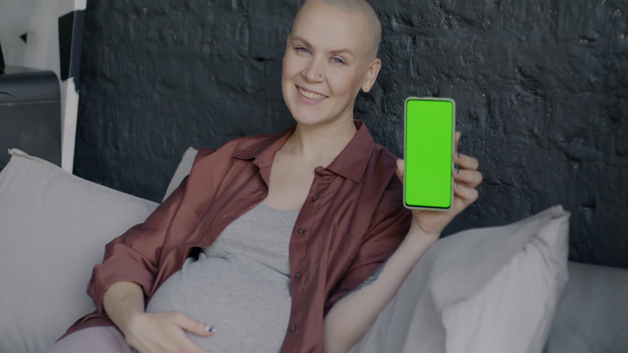 Pregnant woman holding a phone with a green screen
