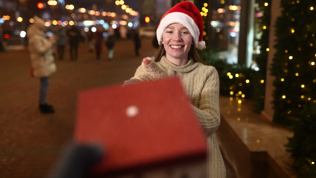 mujer recibiendo un regalo de navidad en la calle por la noche