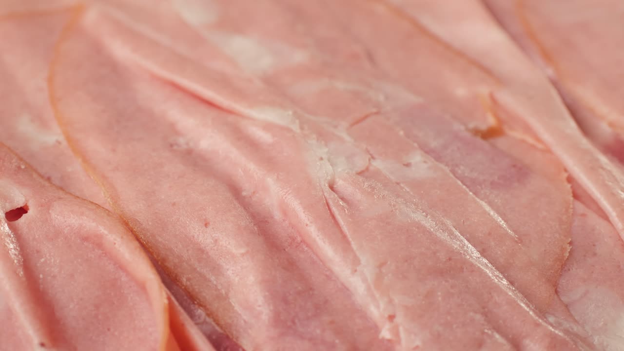 Ham italian mordatella, man Slices Of Traditional Italian antipasti mortadella sausage on a wooden cutting board, close up macro of chicken or turkey jamon, fat breakfast dish.