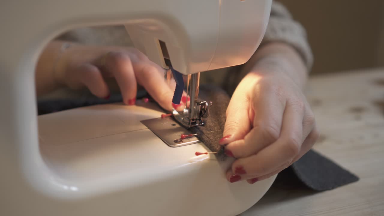 manos femeninas cosiendo tela en la máquina en el lugar de trabajo - cerrar