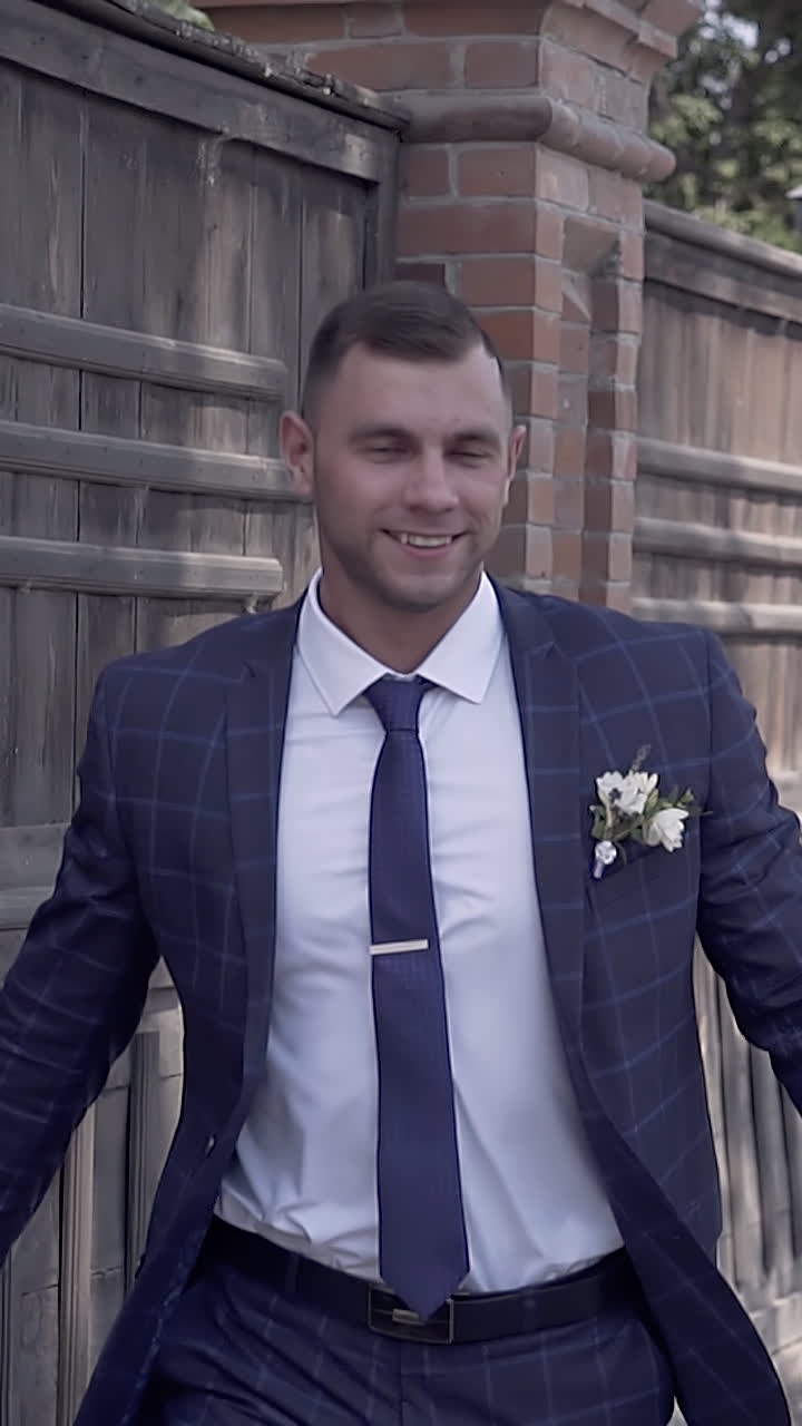 slow motion wonderful young wedding couple in celebratory dressing runs near brown fence against green trees
