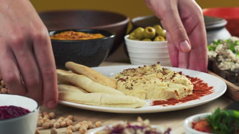 israeli cuisine. putting plate with hummus decorated with paprika and pita close-up. national food, middle eastern culture. vegan chickpea puree snack. appetizer made from mashed chickpeas