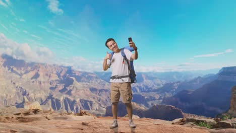 full body of asian male hiker with mountaineering backpack showing peace and thumbs up gesture while taking a selfie while traveling at the top of mountain