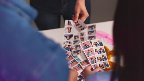 close up of a group of friends having fun looking at prints from photo booth with props 12