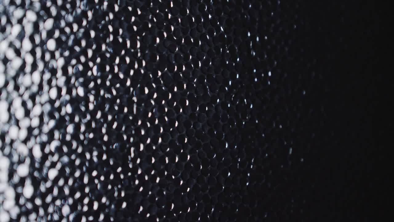 Water trickles onto moody lit dark textured glass window background