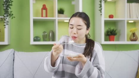 충분한 단백질과 칼 ⁇ 을 섭취하는 젊은 아시아 여성은 요구르트를 먹습니다.