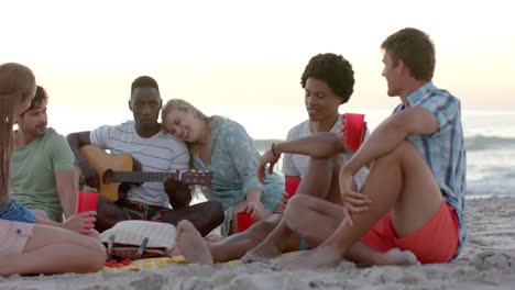 diverse friends enjoy music on the beach at sunset