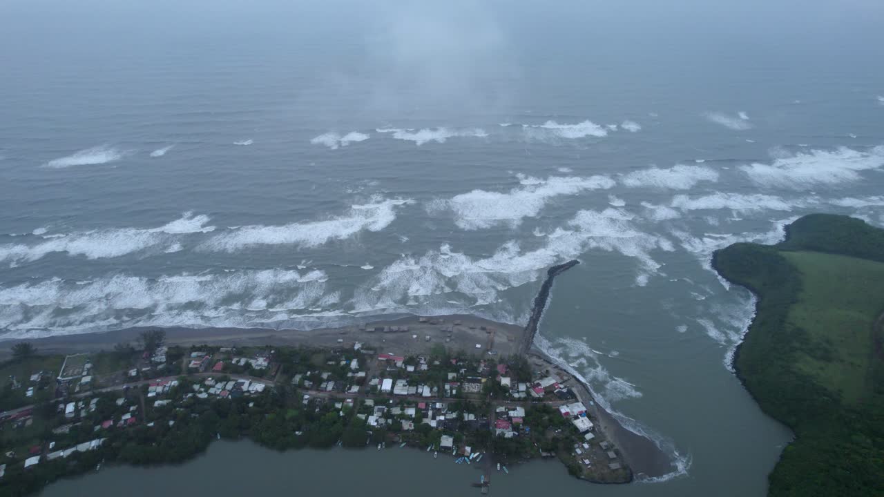 Drone footage approaching to breakwater and waves approaching to coast in Barra de Sontecomapan Veracruz Mexico. Drone goes through a cloud