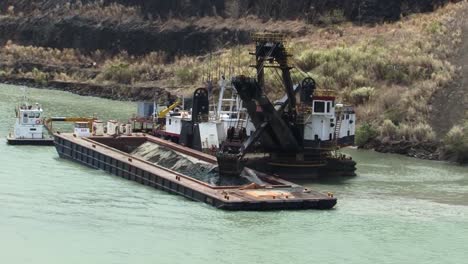 excavadora flotante cargando una barcaza en el lago gatún, canal de panamá