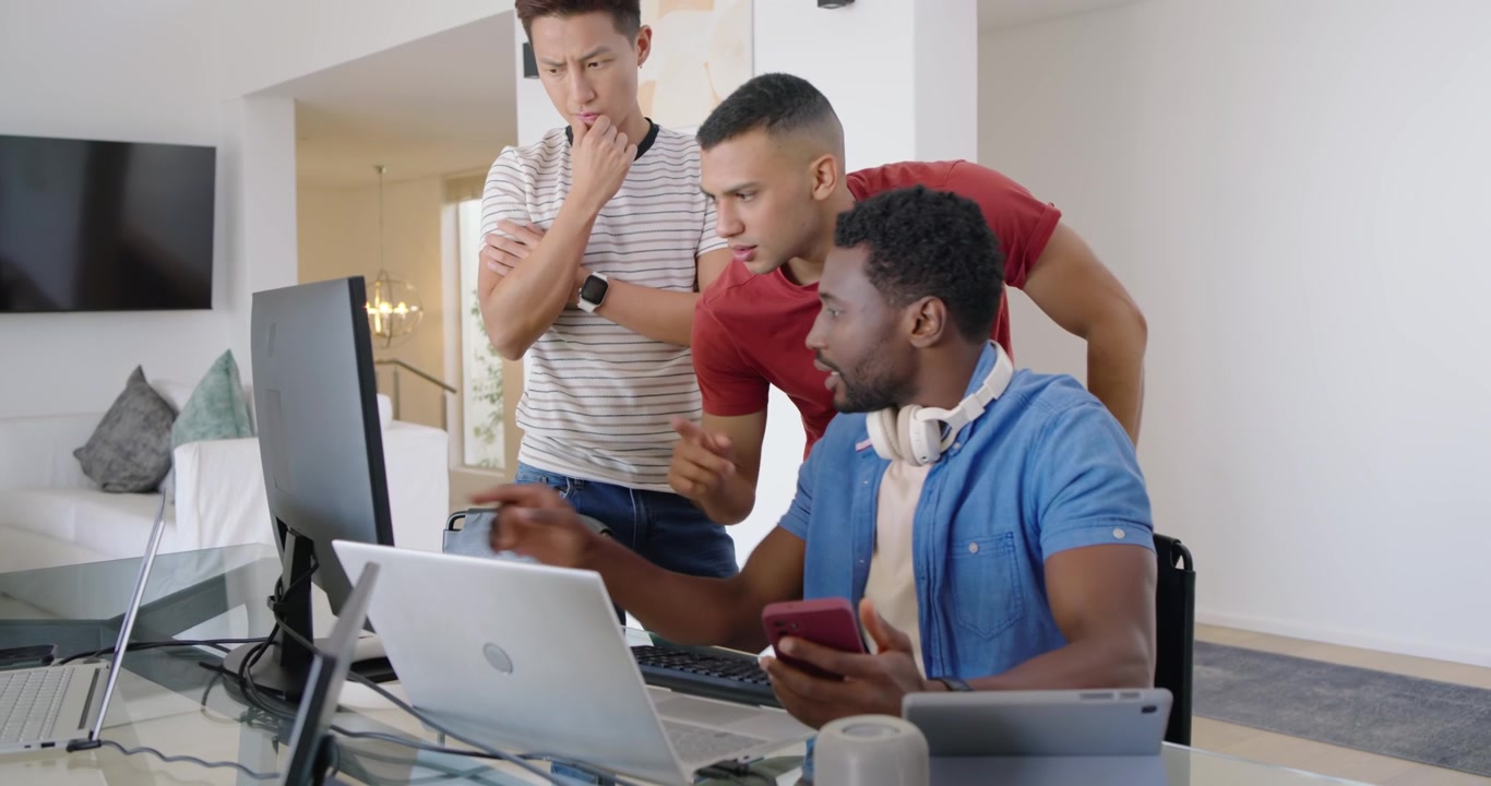 Diverse coworkers clustering at glass desk at home after red-shirt entering, troubleshooting laptop