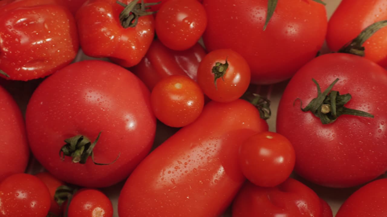 Colorful organic tomatoes. Mix tomatoes background, Several varieties of sliced tomatoes top view. Different assorted colorful tomatoes, heirloom, cherry, rose, beefsteak, cocktail, grape, purple.