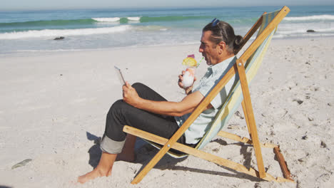 senior caucasian man sitting on sunbeds at the beach.