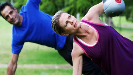 pareja madura haciendo ejercicio con kettlebell en el parque