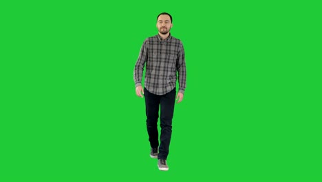 relaxed casual man in jeans and shirt walking and looking to the sides on a green screen, chroma key