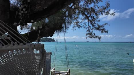 El-Paraíso-Costero-De-Koh-Tao,-Tailandia,-Cuenta-Con-Costas-Bañadas-Por-El-Sol-Y-El-Mar-Que-Se-Extiende-Hasta-El-Horizonte,-Todo-Ello-Visto-Tranquilamente-Desde-Una-Silla-A-La-Sombra-Bajo-Un-árbol-Costero.