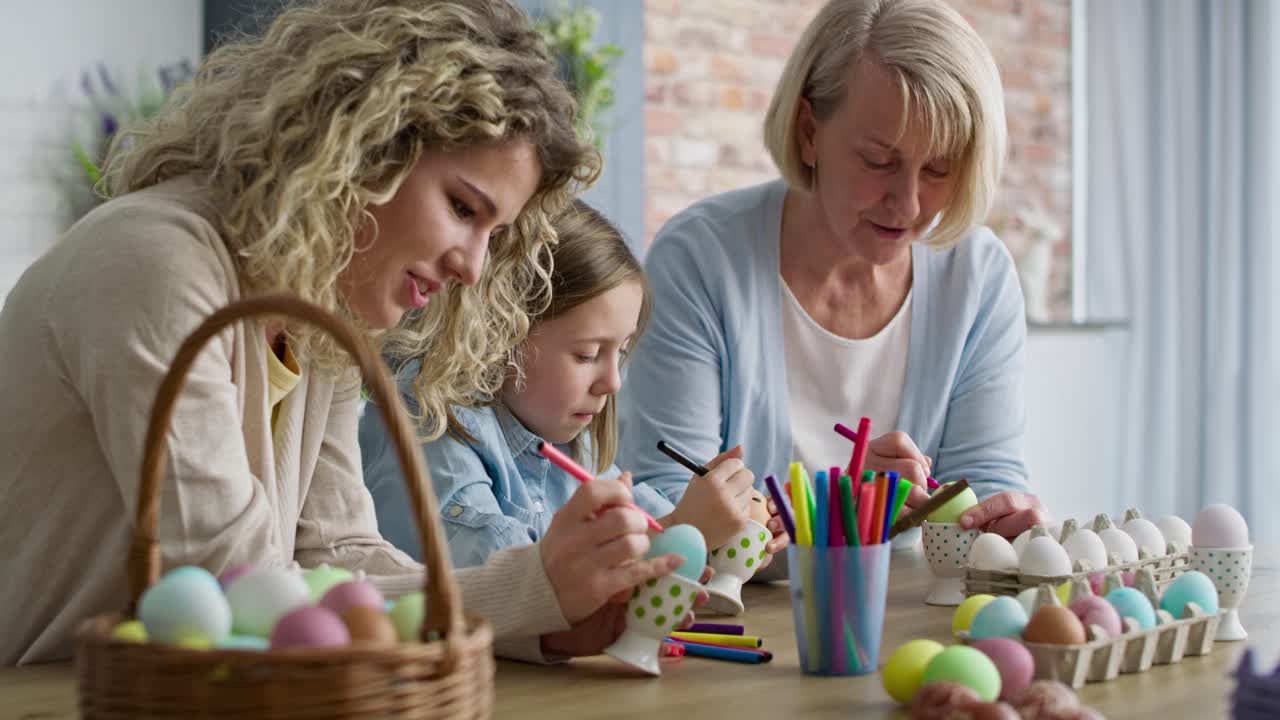 Video of girl with mother and grandma coloring Easter eggs