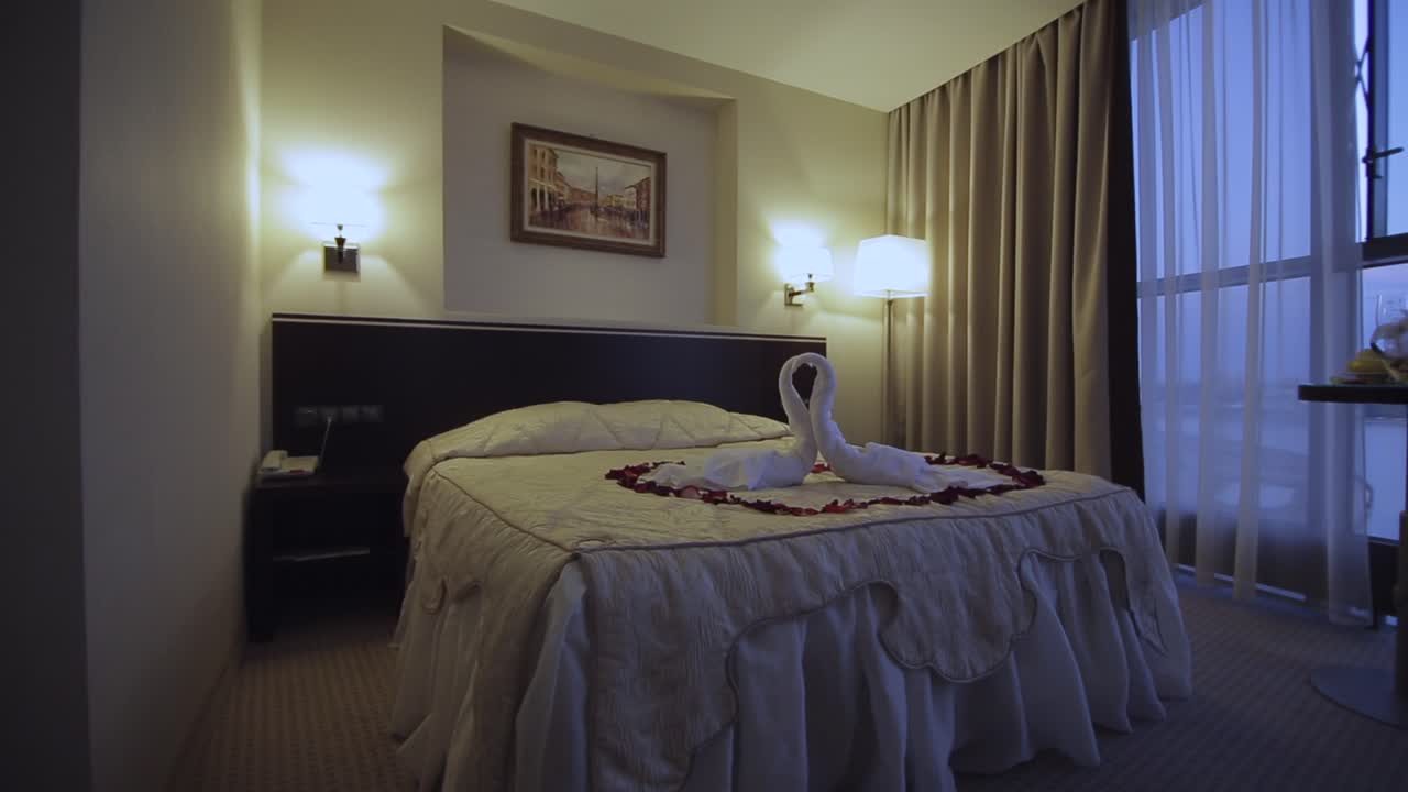 habitación de hotel romántica con toallas de cisne y pétalos de rosa
