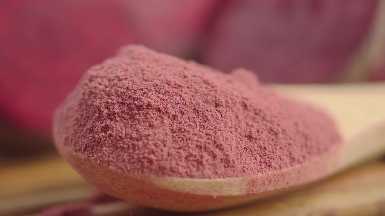Nærbillede af levende lyserødt superfood-pulver på en træske