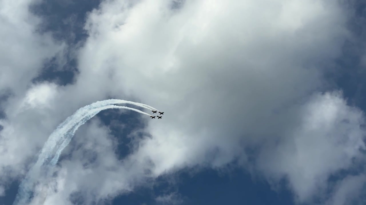 Exhibición de vuelo en formación sobre Iași, Rumanía, durante las celebraciones del centenario del primer vuelo comercial, con aviones dejando estelas de humo contra un cielo dramático lleno de nubes.