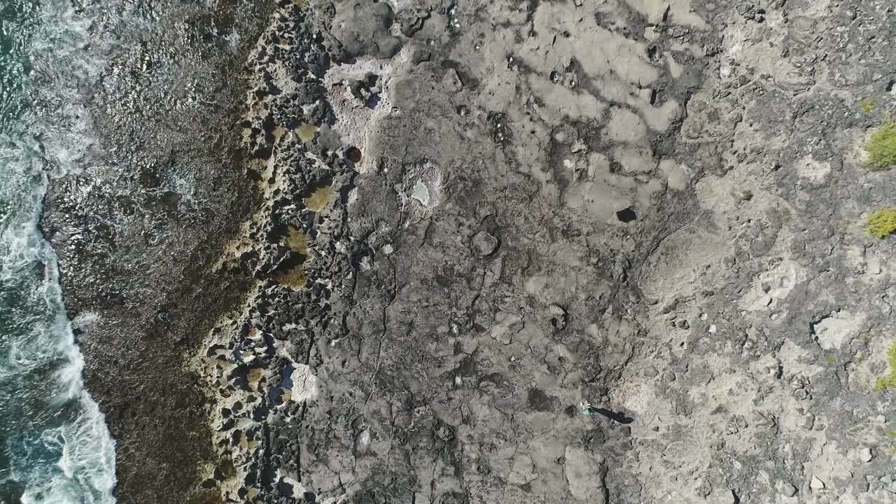 vista ascendente de arriba hacia abajo que revela la costa de rocas volcánicas, olas rompiendo, ko olina, hawaii