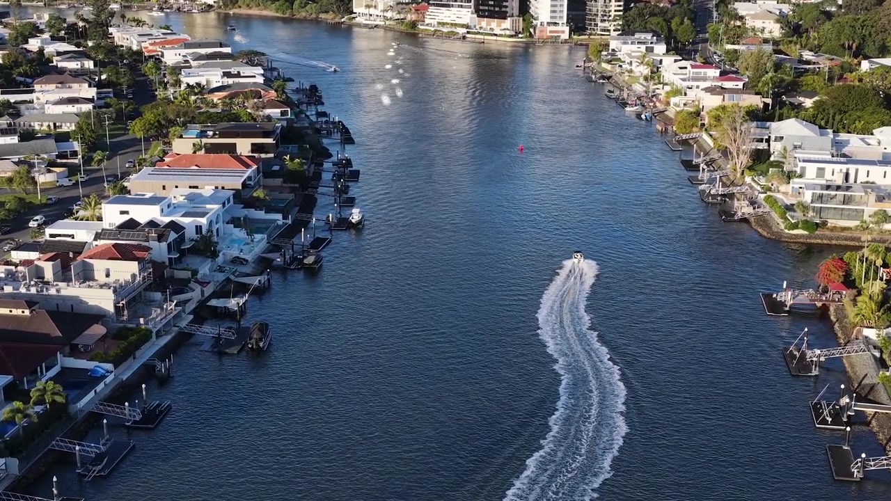 Ripresa aerea con drone della scia di una barca su un fiume fiancheggiato da ville sul lungofiume