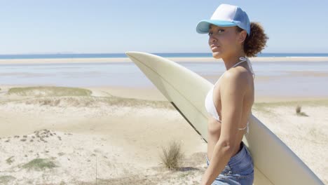 Smiling-sporty-woman-embracing-surfboard