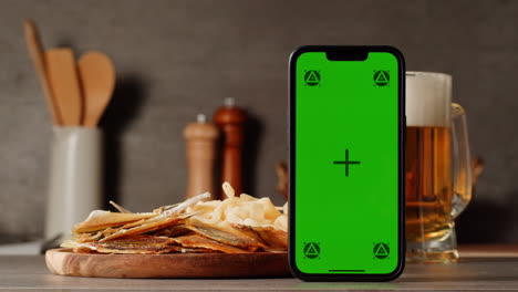 dried fish snack with green screen phone and beer