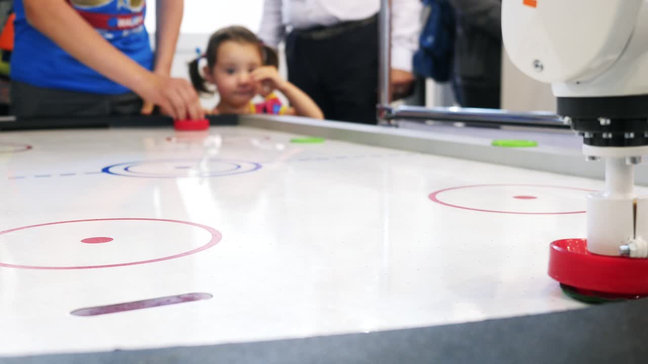 Bambini che giocano a air hockey con un braccio robotico