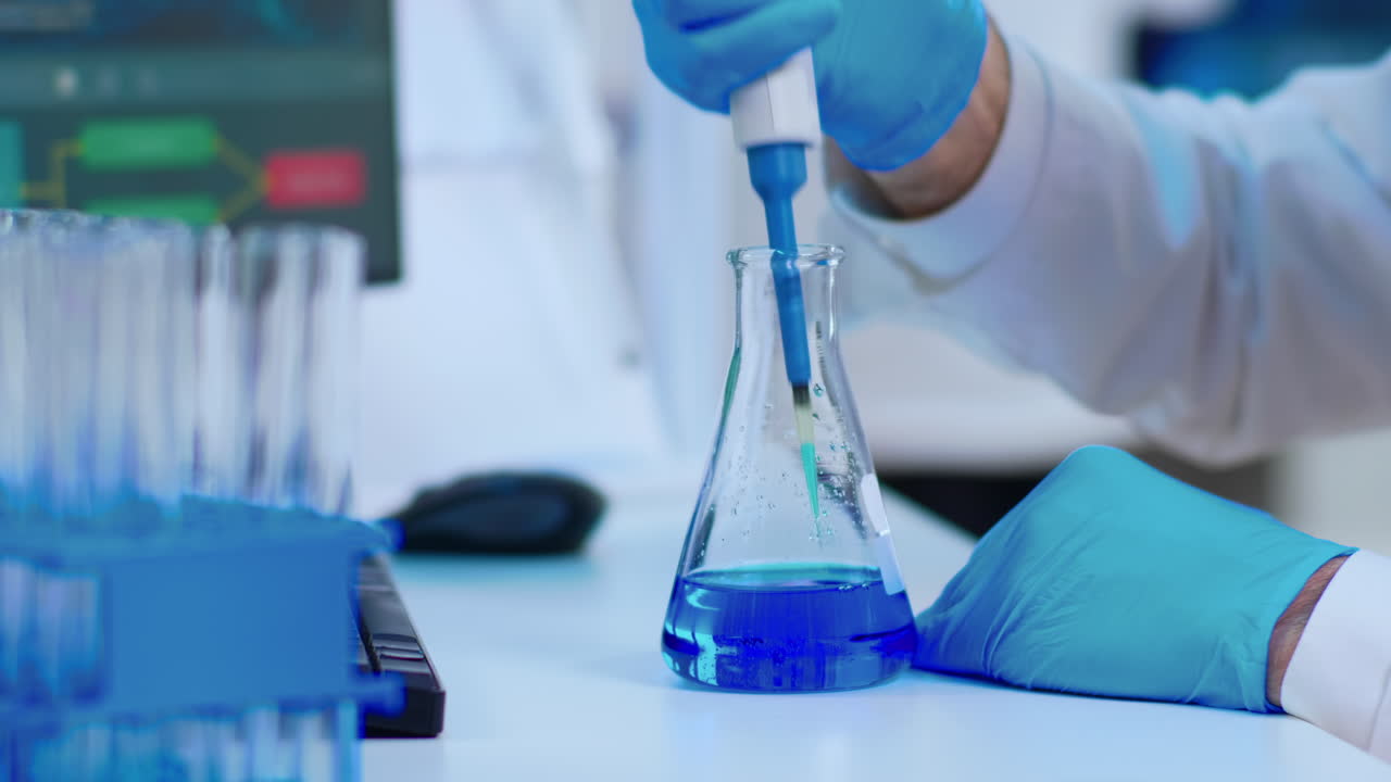 Close up of scientist filling test tube with liquid using pipette