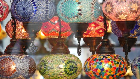 colourful turkish lamps from glass mosaic glowing. arabic multi colored authentic retro style lights. many illuminated moroccan craft lanterns. oriental islamic middle eastern decor. shiny folk shop