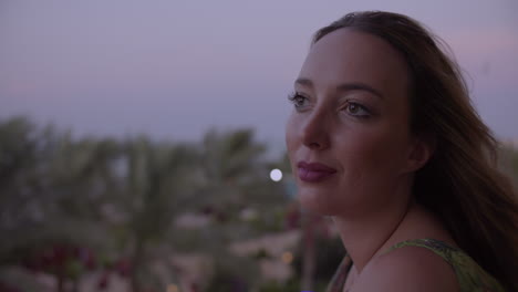 mujer joven en un balcón mirando a lo lejos y disfrutando del viento por la tarde