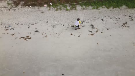 volunteer collecting plastic waste during beach clean-up in rayong thailand aerial view