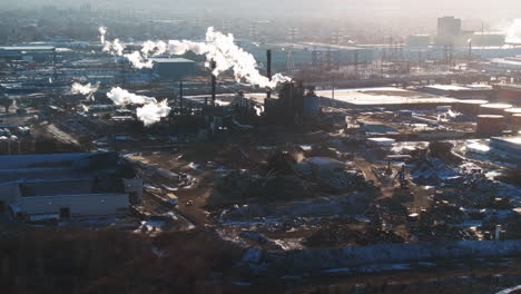 Industrial-area-with-smokestacks-emitting-steam-on-a-clear-day,-aerial-view