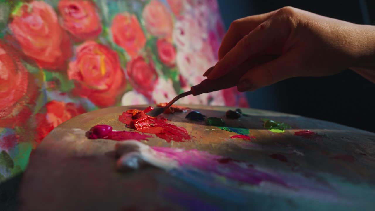 Artist's Hand Mixing Vibrant Paint Colors on a Palette