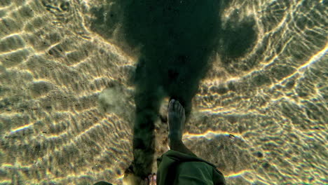 barefoot person standing and casting shadow in tropical beach