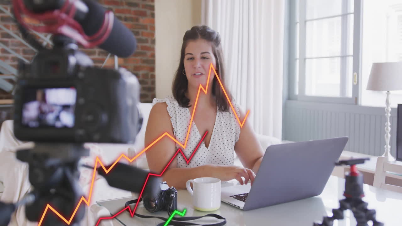 Woman working on laptop with camera and rising graph animation overlay