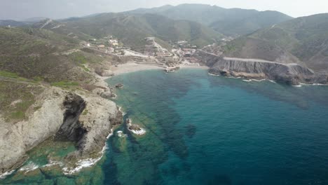 Aerial-establishing-shot-of-the-beautiful-bay,-crystal-waters,-and-sandy-beaches-of-a-Cape-Argentiera---former-silver-mines-in-Sardinia,-Italy