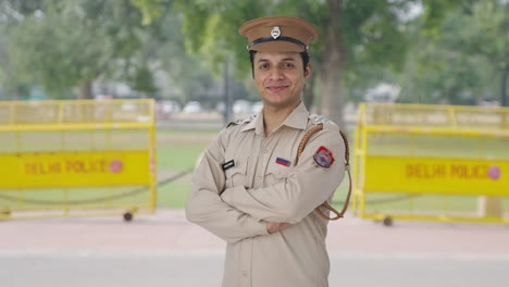 retrato de un feliz oficial de policía indio de pie con las manos cruzadas