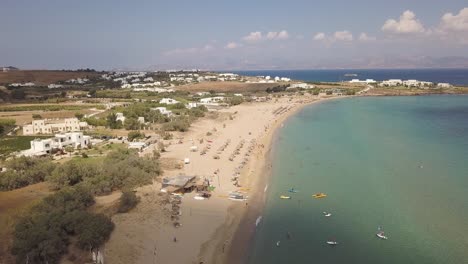 Tiro-De-Drones-En-Aumento-De-Turistas-Disfrutando-De-Las-Arenas-Doradas-De-Una-Playa-Pública-En-La-Isla-Griega-De-Paros