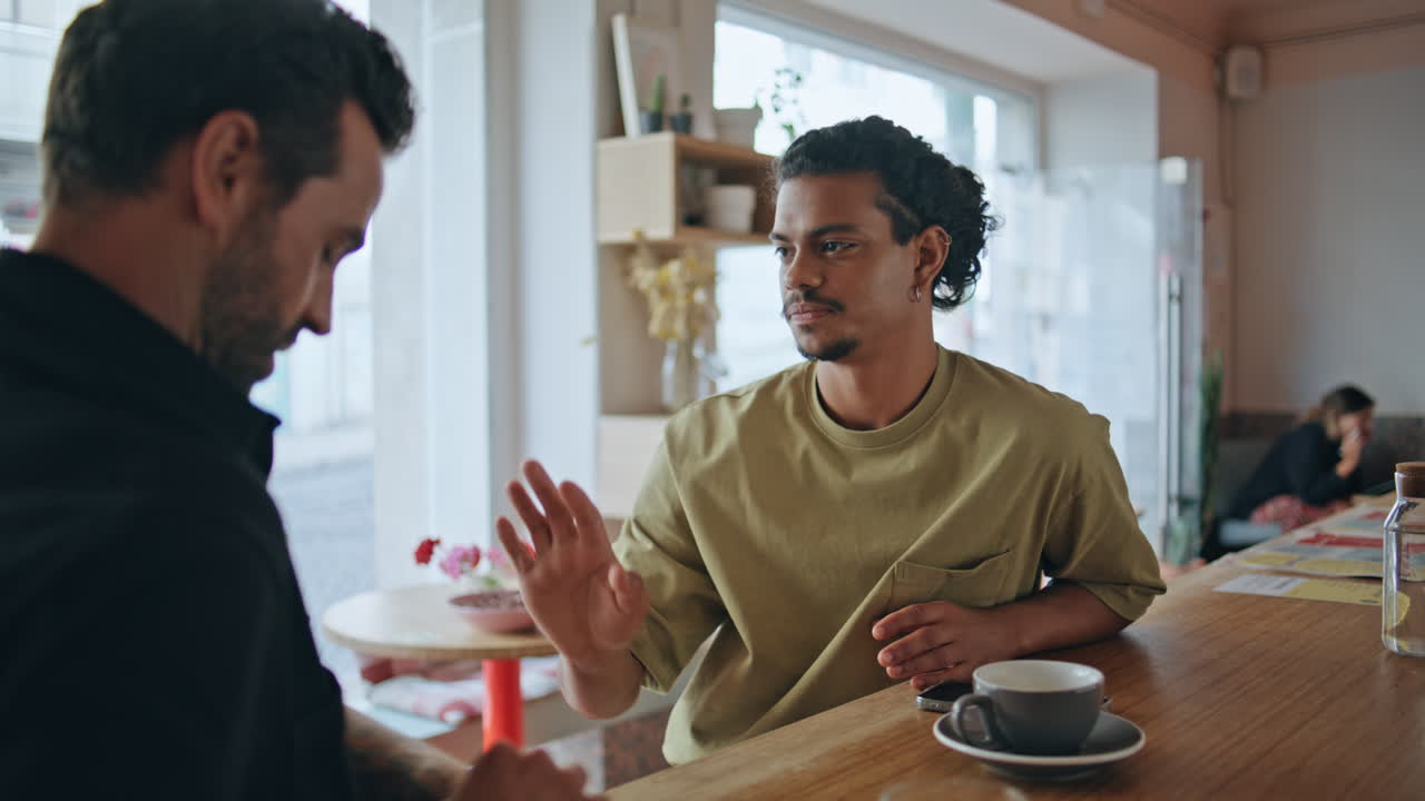 Multiethnic men flirting cafe close up. Two relaxed guys talking in cafeteria