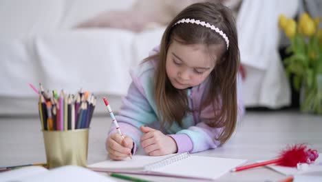 una niña dibujando en el suelo.