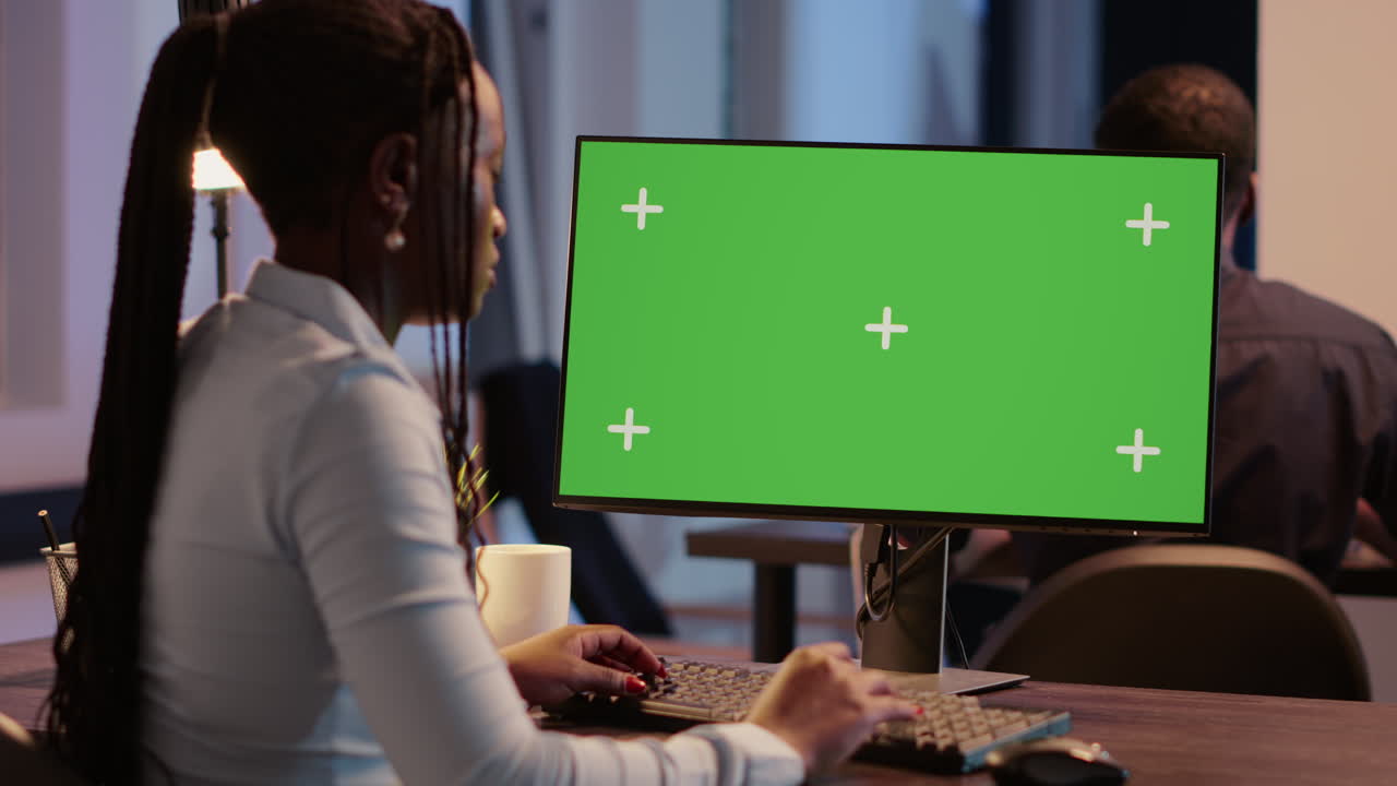 Woman working on computer with green screen