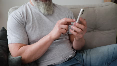 Vista-Cercana-De-Las-Manos-Del-Hombre-Sosteniendo-El-Teléfono-Inteligente