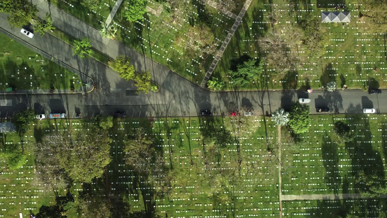 top down drone tiro de la carretera en un parque de cementerio conmemorativo, con los coches que pasan por