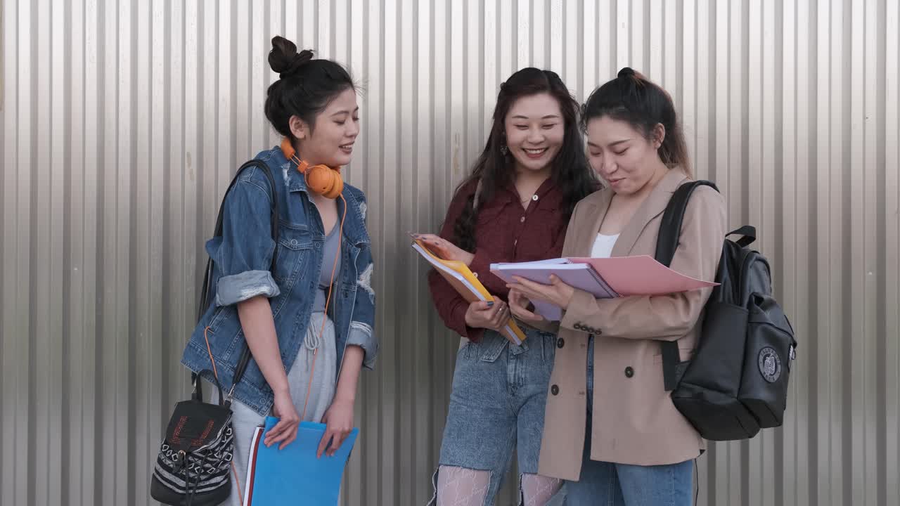 Portrait of a group of asian woman college students talking together outdoors on the street.