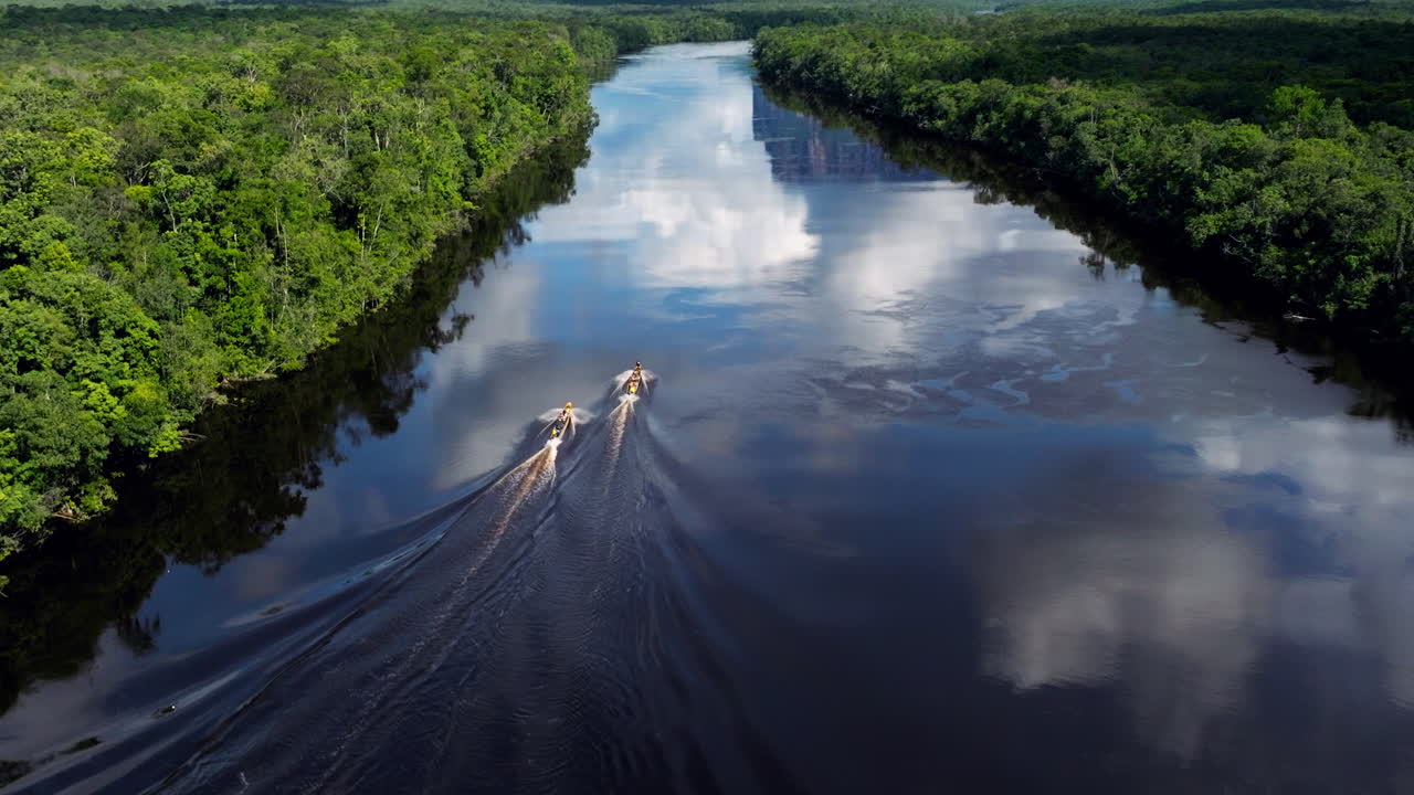 Boats on a river in a lush forest with mountains in the background