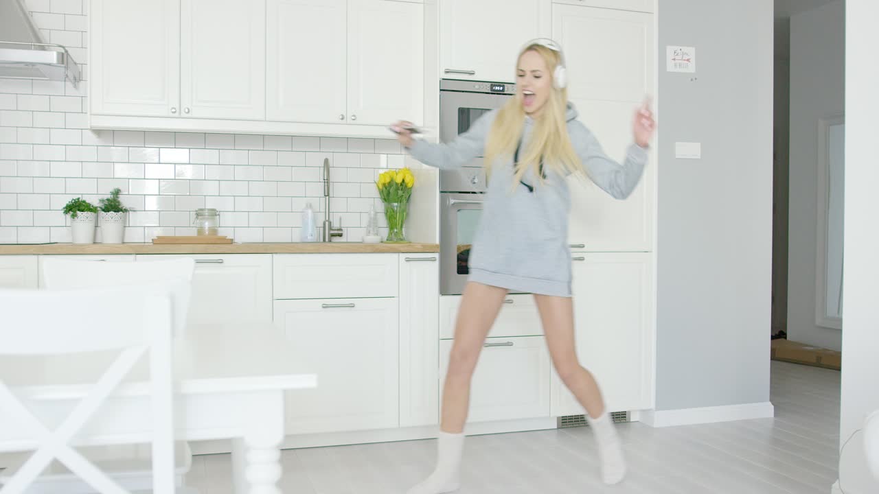 Giovane ragazza espressiva che balla in cucina