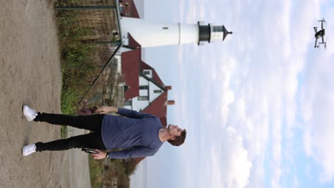 creador de contenido lanzando un dron de la mano con el faro de portland head en el fondo