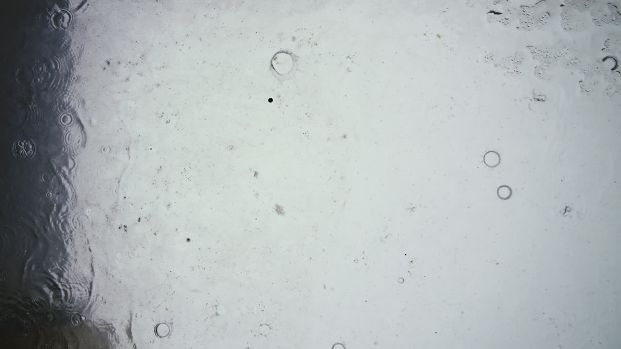 Raindrops Falling and Dripping on a Wet Glass Surface
