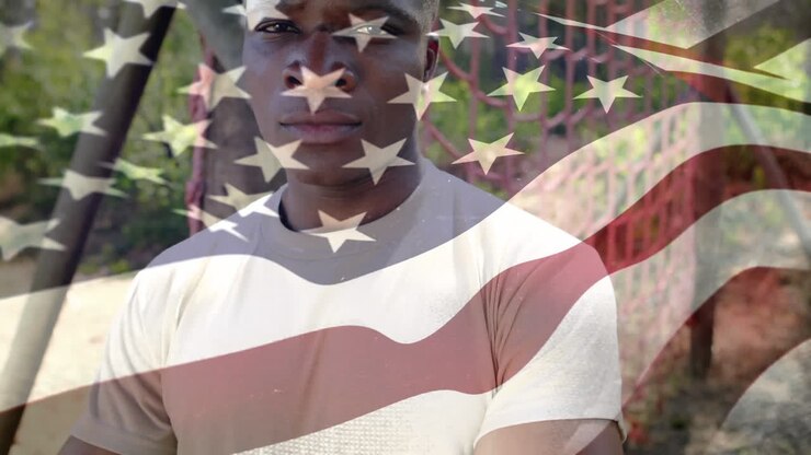 Soldato afroamericano con la bandiera degli Stati Uniti che sventola in primo piano.